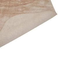 GlobeWest Tepih Curve Rug in dusty rose with subtle geometric pattern and rounded edges, handwoven with soft sheen, shown folded to display texture and backing.