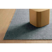 GlobeWest Tepih Neptune hand-loomed ocean green wool blend rug on wooden floor with furniture leg visible