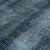 Close-up of GlobeWest Tepih Tide Rug in marine color with a textured ripple design resembling ocean waves, hand woven from viscose and wool.