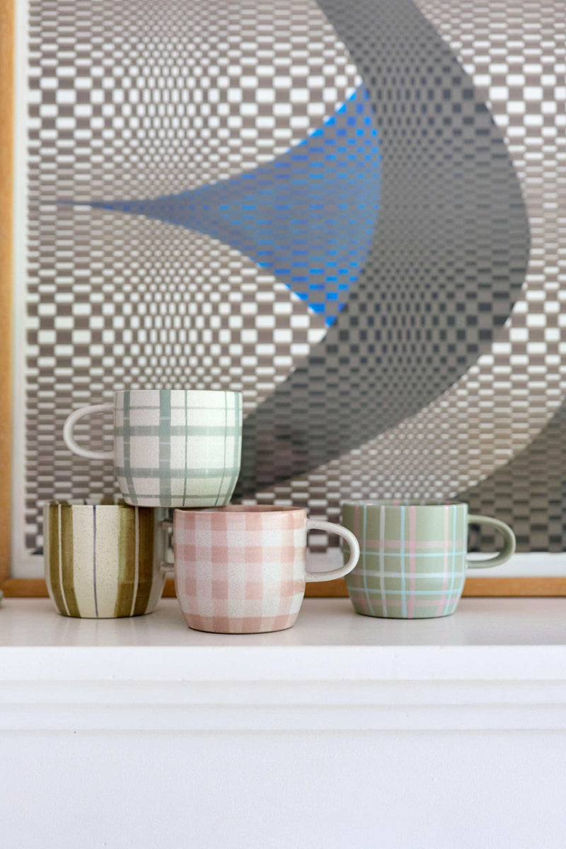 Set of four Robert Gordon mugs with hand-painted tartan, stripes, and gingham checks in muted colors on a white surface.