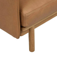 Close-up of camel Tolv Pensive Occasional Chair showing high-quality leather upholstery and light oak wooden leg