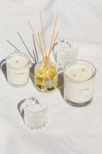 Grace and James reed diffuser styled with candles on linen