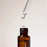 Amber glass bottle of Gentle Habits Ritual Diffuser Oil with dropper releasing a drop of oil above it