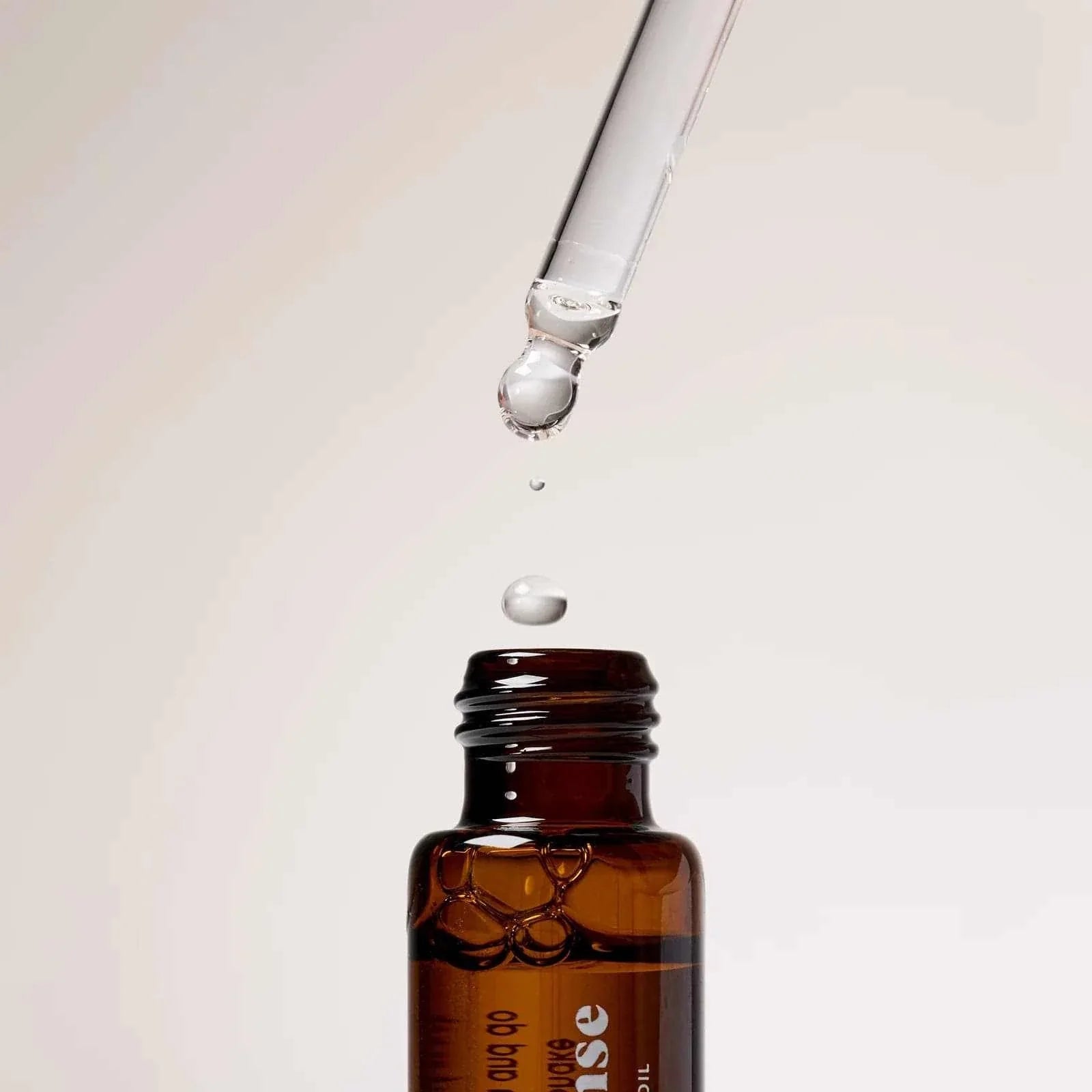 Amber glass bottle of Gentle Habits Ritual Diffuser Oil with dropper releasing a drop of oil above it