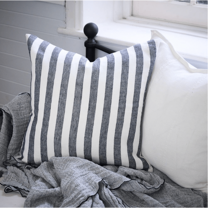 Eadie Lifestyle Santi Linen cushion with white and navy stripes on a bed with gray linen blanket