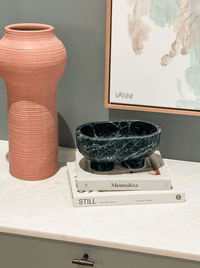 CoTheory Marble Footed Oval Tray Verdi Alpi on books with terracotta vase and abstract wall art
