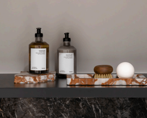 Palazzo Scalloped Marble Bar Tray in Brown Calacatta holding bathroom essentials on a black shelf