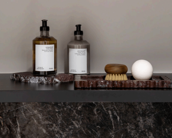 CoTheory Rosso Levanto scalloped marble bar tray with toiletries and brush on black shelf