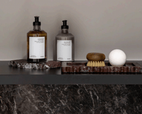 CoTheory Rosso Levanto scalloped marble bar tray with toiletries and brush on black shelf