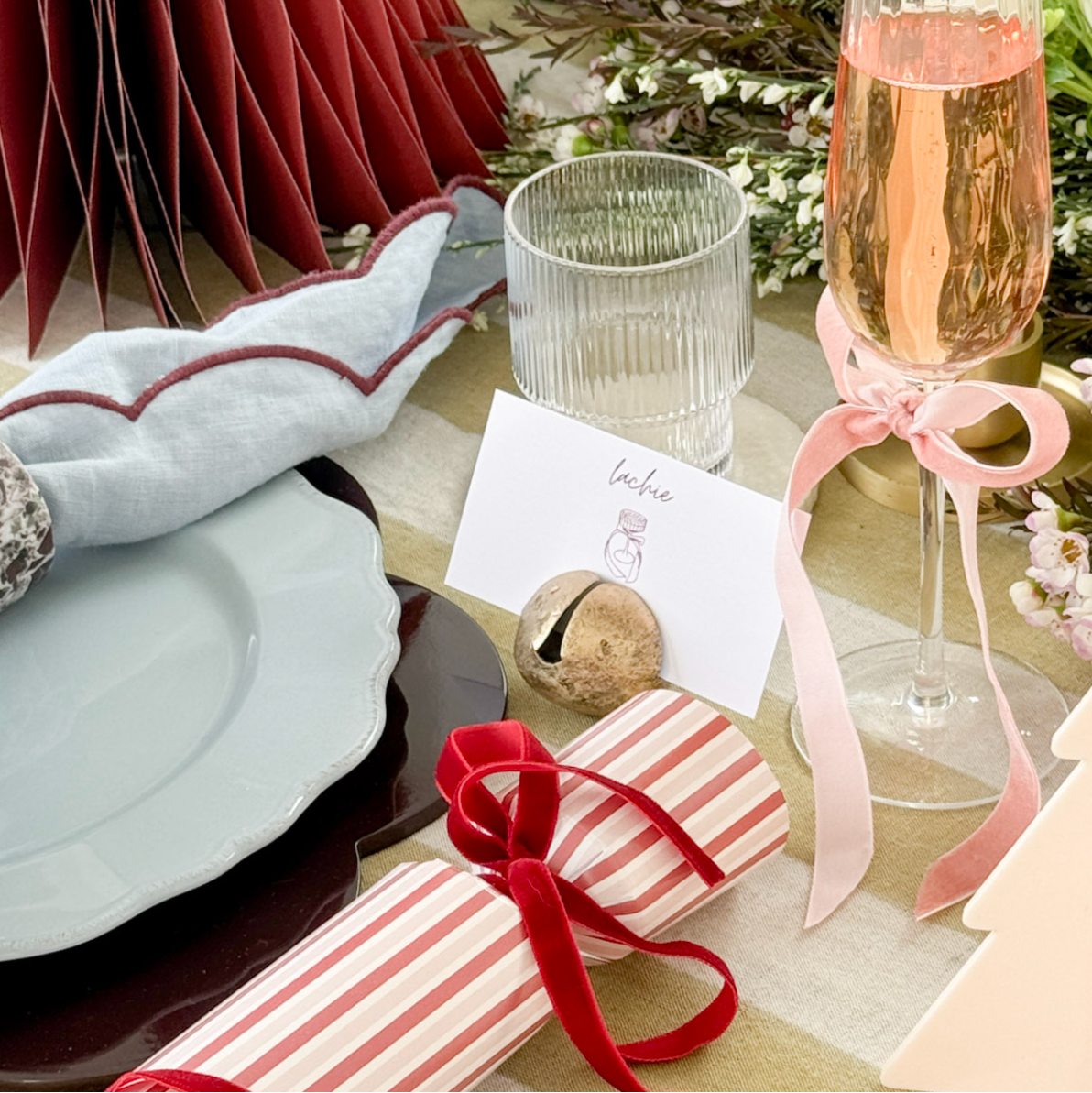 Decorative table setting with a glass of pink champagne, napkin, and small gift box.