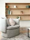 Modern living room with styled wooden shelves featuring minimalist decor and a cozy gray armchair with striped cushions
