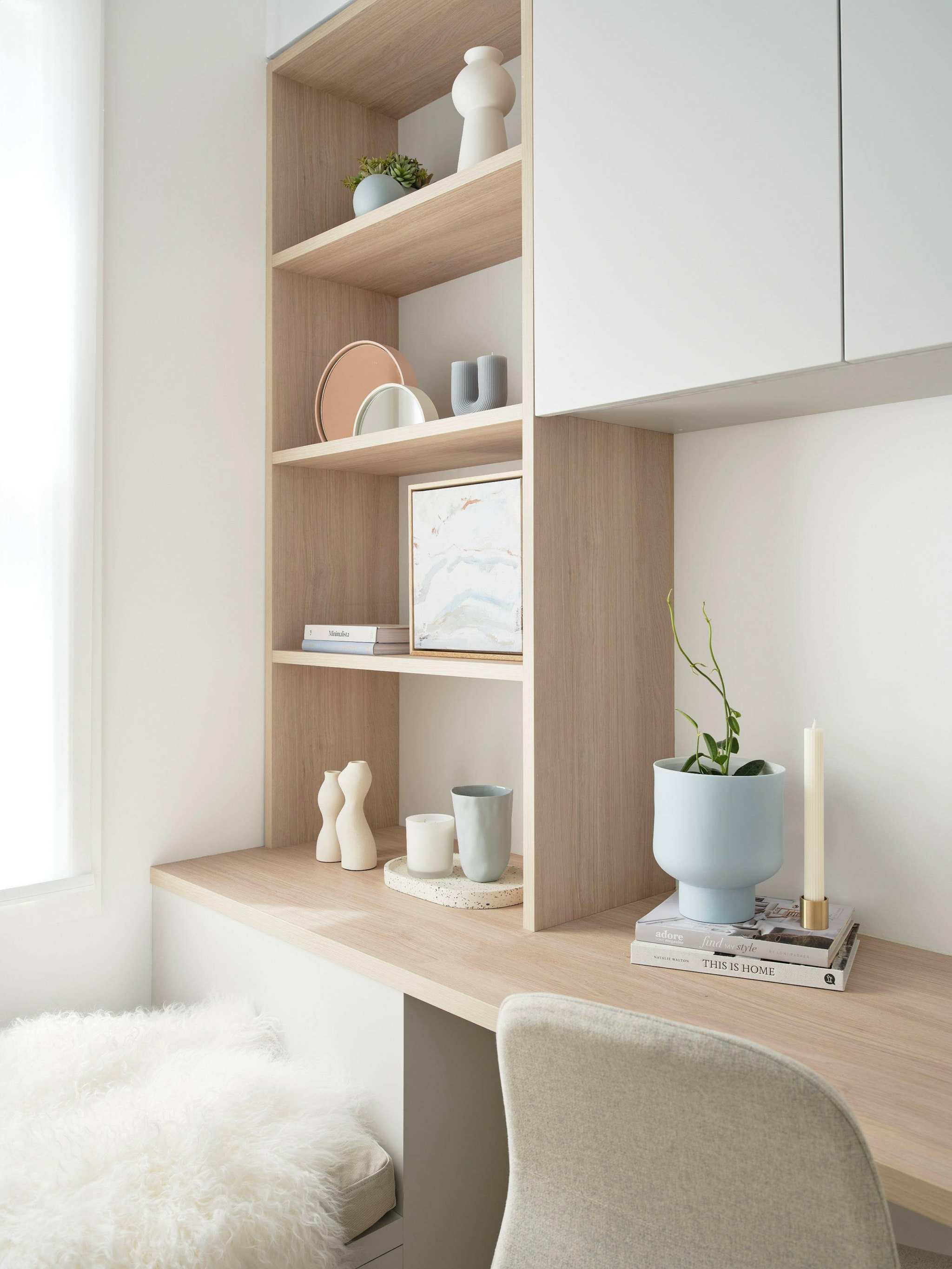 Minimalist styled wooden shelves with decorative objects and a workspace area in a bright room