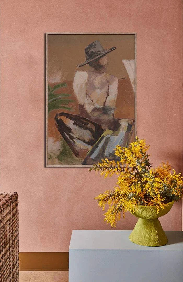 Limited edition Marcia Priestley fine art canvas print Traveller 2 with floating oak frame on pink wall and yellow flowers in green vase.