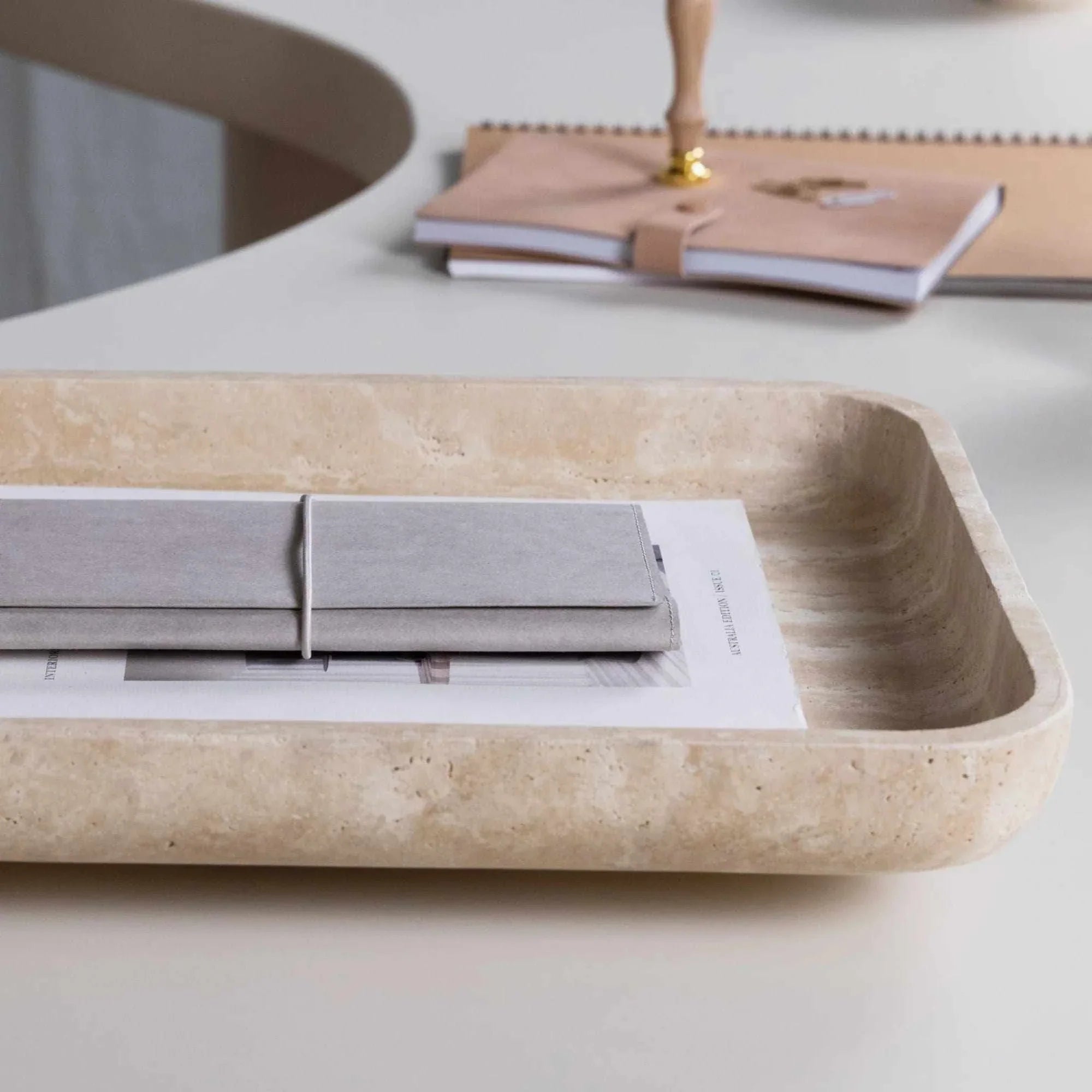 Beige CoTheory Travertine footed letter tray holding notebooks on a white desk