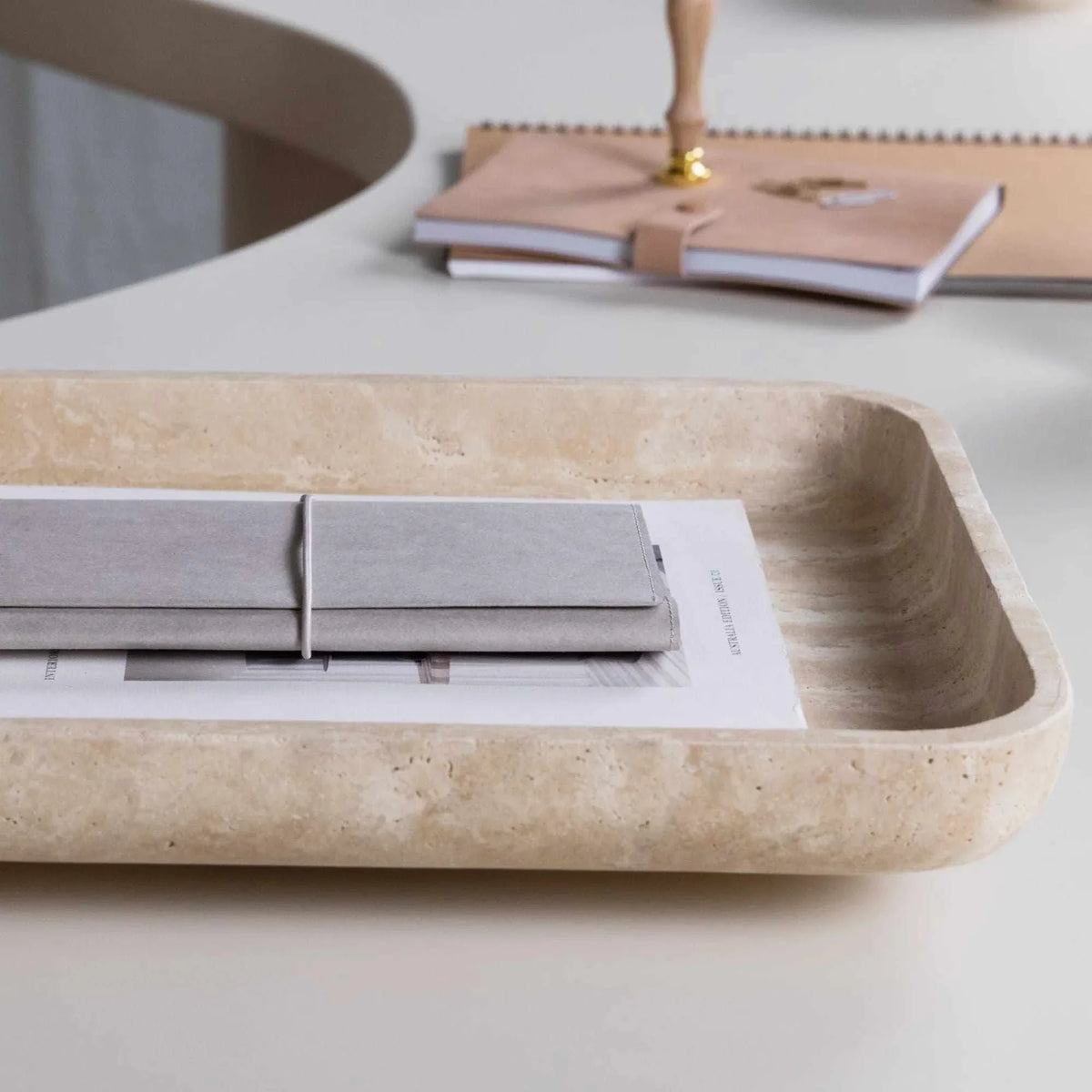 Beige CoTheory Travertine footed letter tray holding notebooks on a white desk
