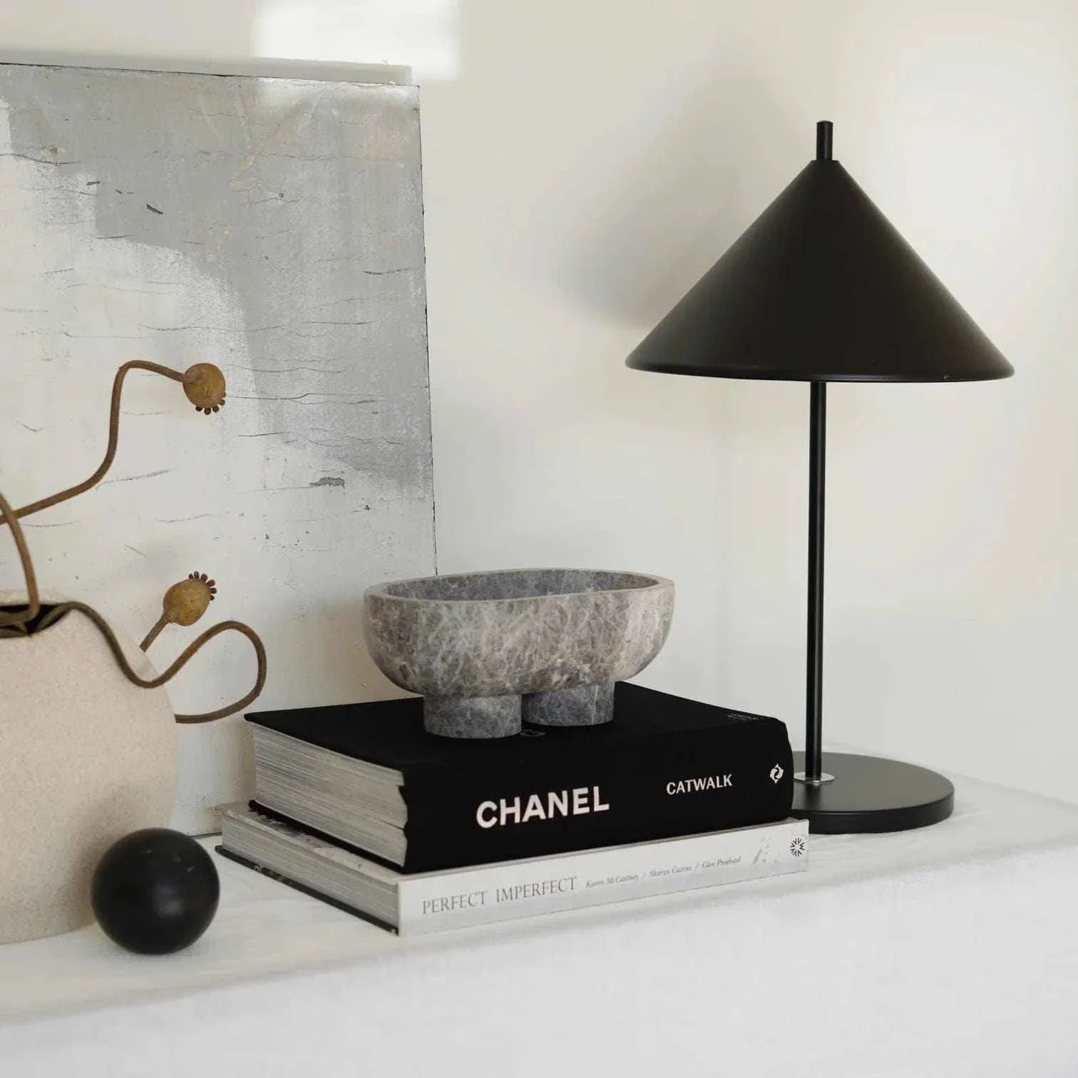 CoTheory marble footed oval tray in tundra grey on books beside black modern lamp