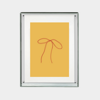 minimalist digital print of red ribbon bow on mustard yellow background in a clear frame