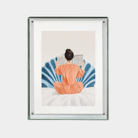 Framed digital print of person in orange pajamas reading newspaper on bed against blue decorative background