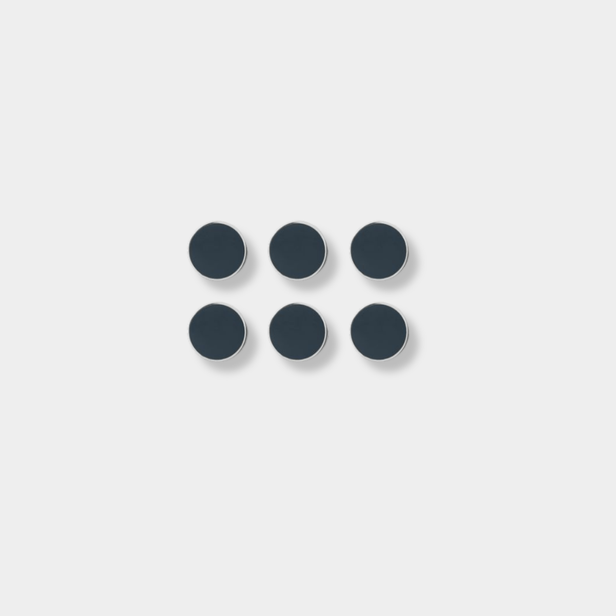Set of six slate-colored Mustard Made magnetic buttons with smooth flat surfaces and shiny edges.