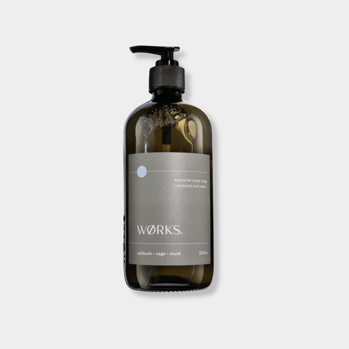Works Body Soap in a 500ml smoky grey glass bottle with pump, featuring saltbush, sage, and musk fragrance, crafted with plant-based ingredients and traditional methods.