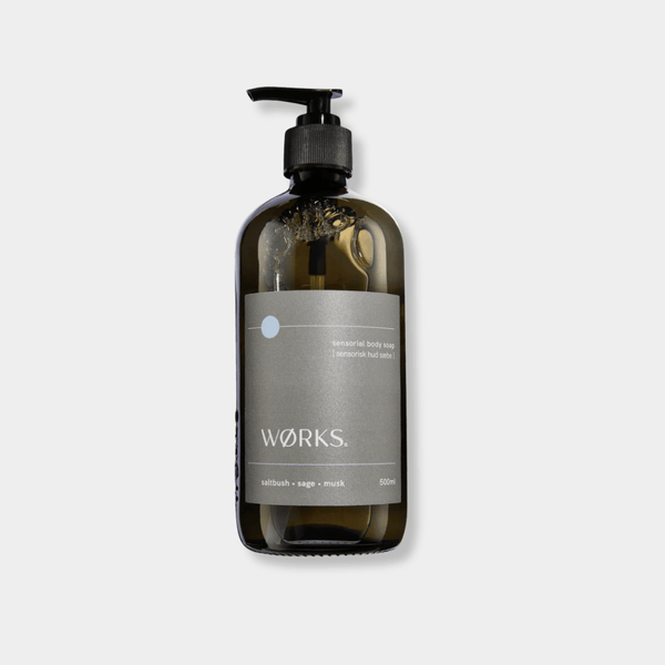 Works Body Soap in a 500ml smoky grey glass bottle with pump, featuring saltbush, sage, and musk fragrance, crafted with plant-based ingredients and traditional methods.