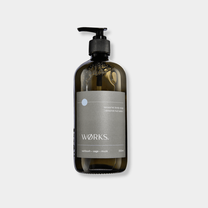 Works Body Soap in a 500ml smoky grey glass bottle with pump, featuring saltbush, sage, and musk fragrance, crafted with plant-based ingredients and traditional methods.