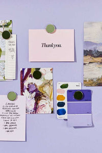 Mustard Made The Buttons sage green magnets holding notes and cards on a lavender wall