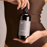Hand holding amber Works Body Soap in 500ml dark glass bottle with pump dispenser.