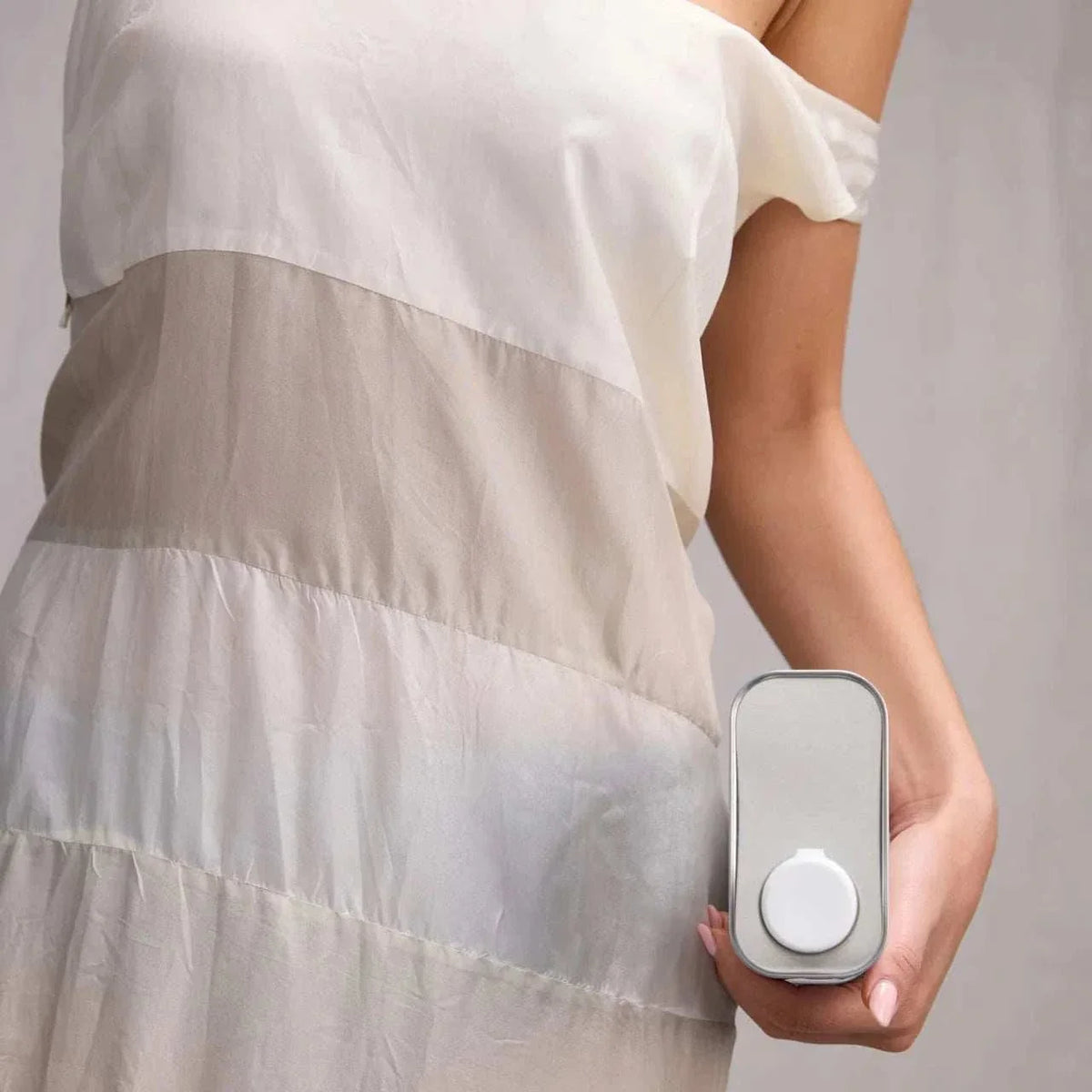 Hand holding Works Body Soap amber 1L refill aluminium canister with built-in pourer against light neutral background