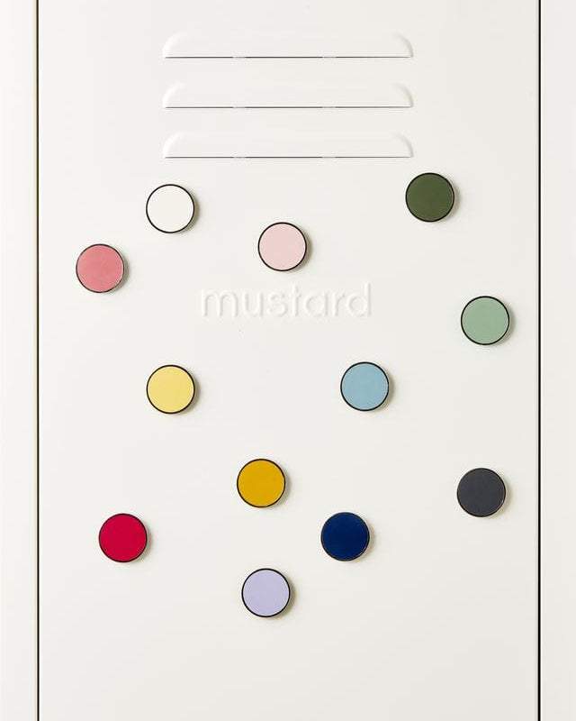 Mustard Made magnetic buttons in various colors arranged on a white surface with embossed logo