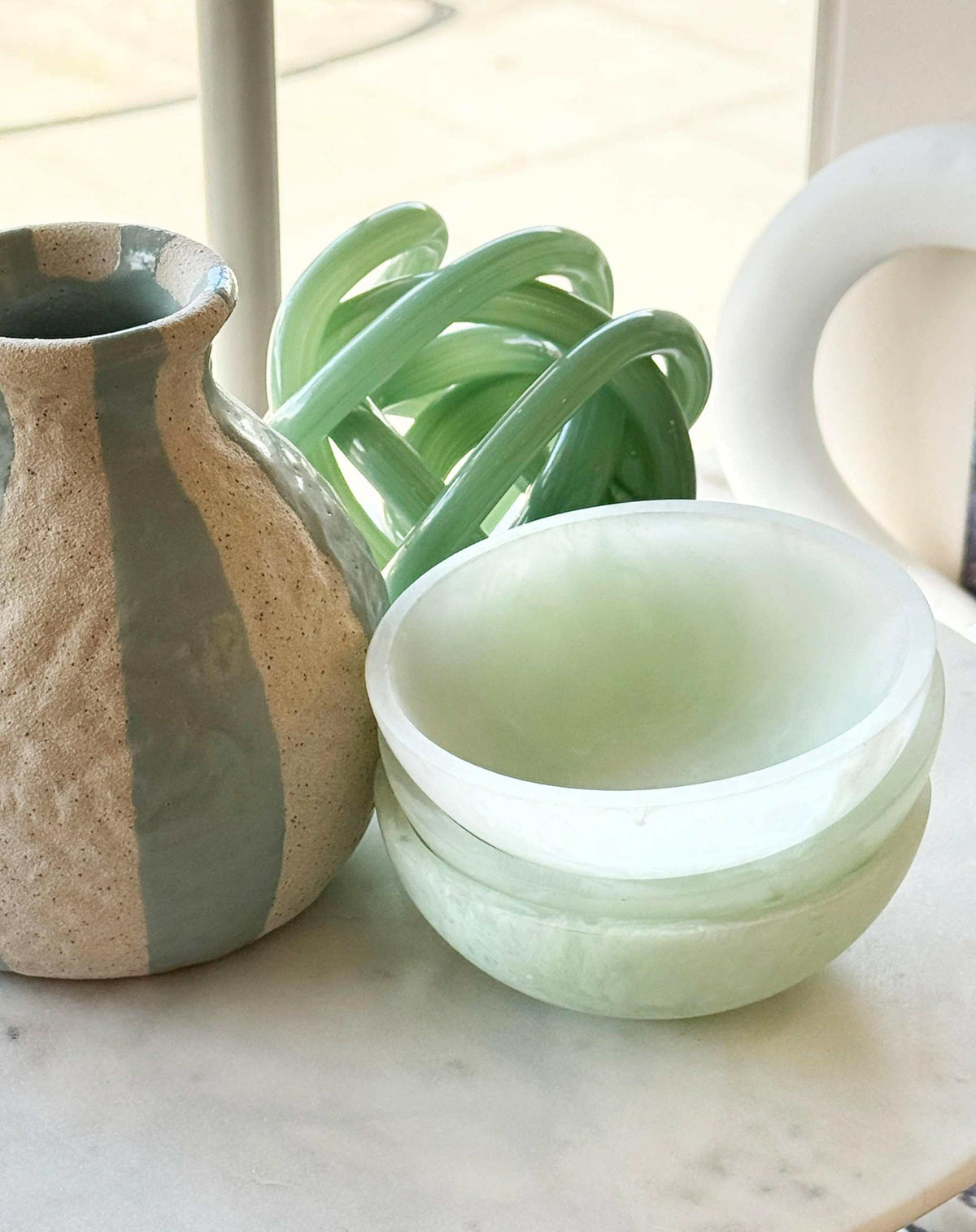 Ada Resin Small Bowl in mint color stacked next to a decorative vase on a marble surface