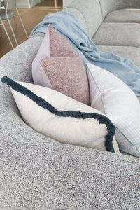Aura Reversible Cushion on a sofa showing the lilac side