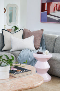 Aura Reversible Cushion styled in a living room with a grey sofa and marble coffee table