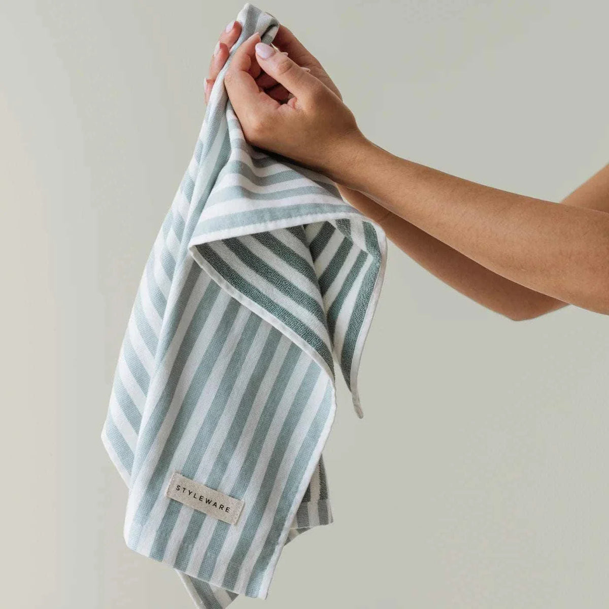 Person holding a green and white striped Styleware Between The Lines Tea Towel in Matcha color