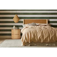 Natural ash Artie Bedhead mounted on bed with beige bedding and striped wall background