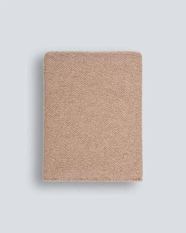 Blush Baya Cromwell Throw Blanket with textured cotton blend bouclé weave and short raw-edge fringing draped over sofa