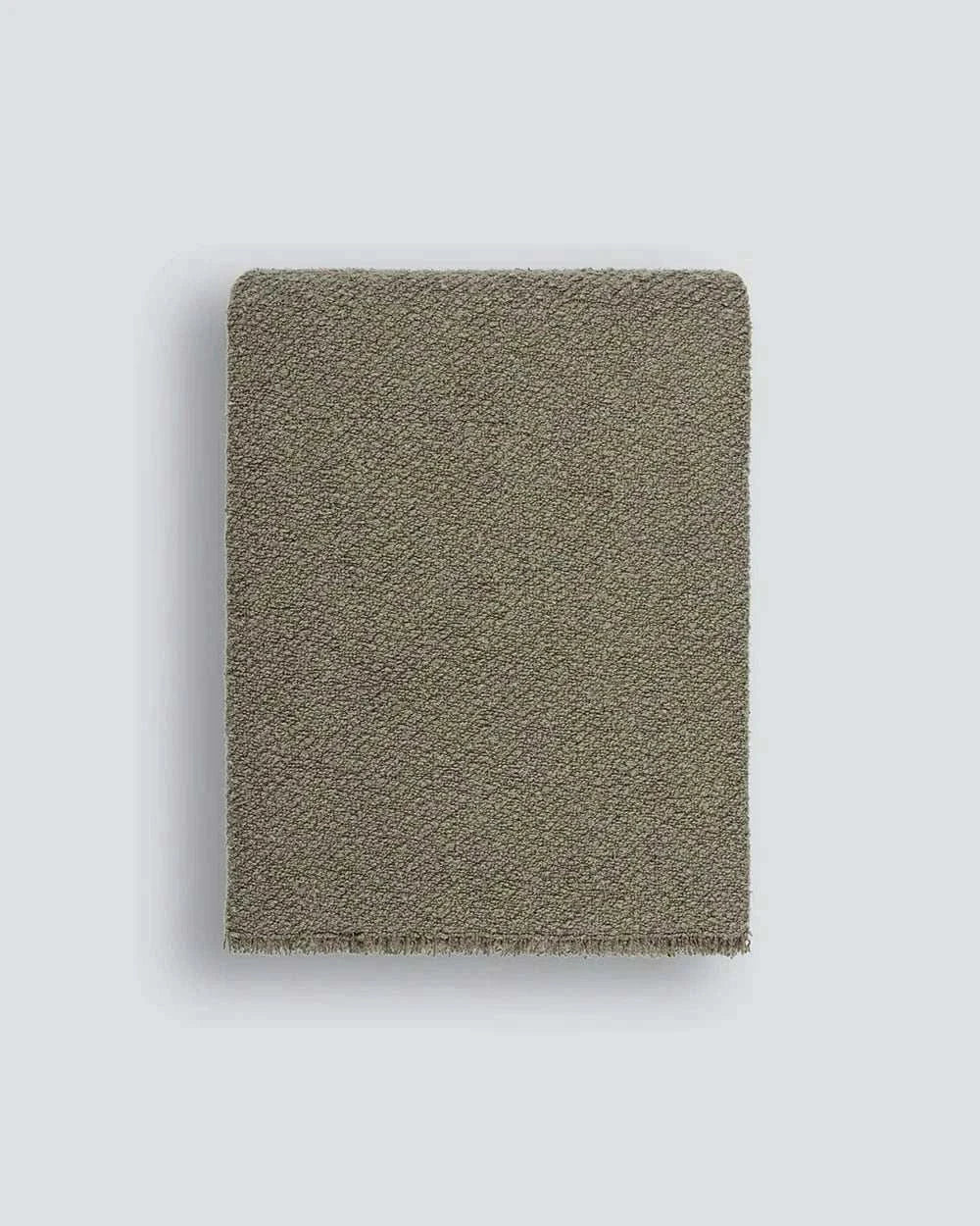 Baya Cromwell Throw Blanket in dusky olive green cotton blend bouclé texture draped on sofa