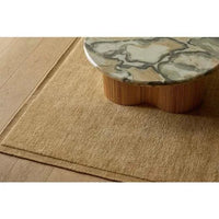 GlobeWest Bower Frame Rug in butter color, hand woven wool area rug beneath marble top wooden coffee table on wooden floor