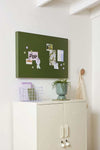 Lilac Mustard Made magnetic buttons holding notes on a green board above a white cabinet with plant and decor.