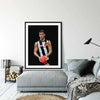 Framed Dom Gauci Kids Art Print of AFL player Nick Daicos in Collingwood FC jersey displayed above grey couch in modern living room