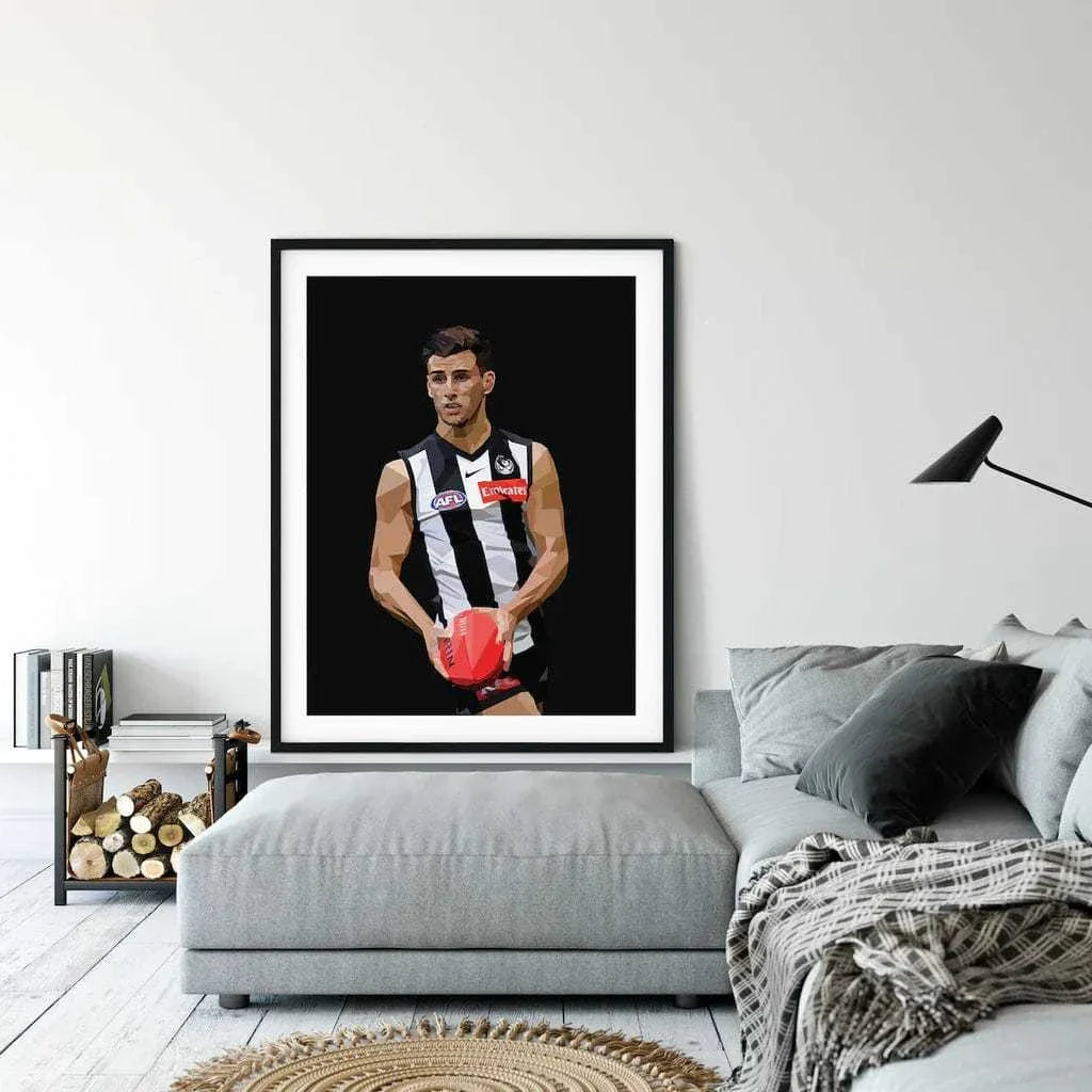 Framed Dom Gauci Kids Art Print of AFL player Nick Daicos in Collingwood FC jersey displayed above grey couch in modern living room