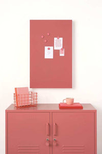 Berry-colored magnetic story board with powder coated finish mounted on wall above matching storage cabinet