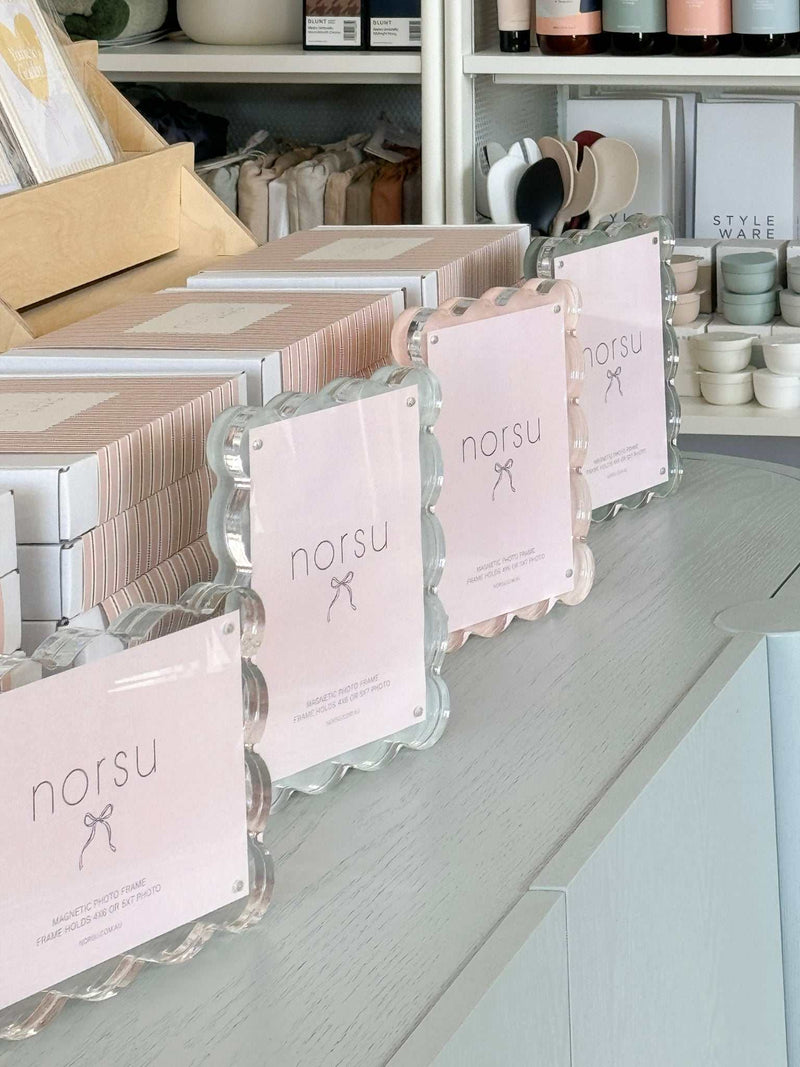 norsu Studio scalloped magnetic photo frames with blush backgrounds displayed on a white countertop in a retail setting