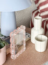 norsu Studio scalloped magnetic photo frame with blush background displayed on a table beside a lamp and ceramic vases