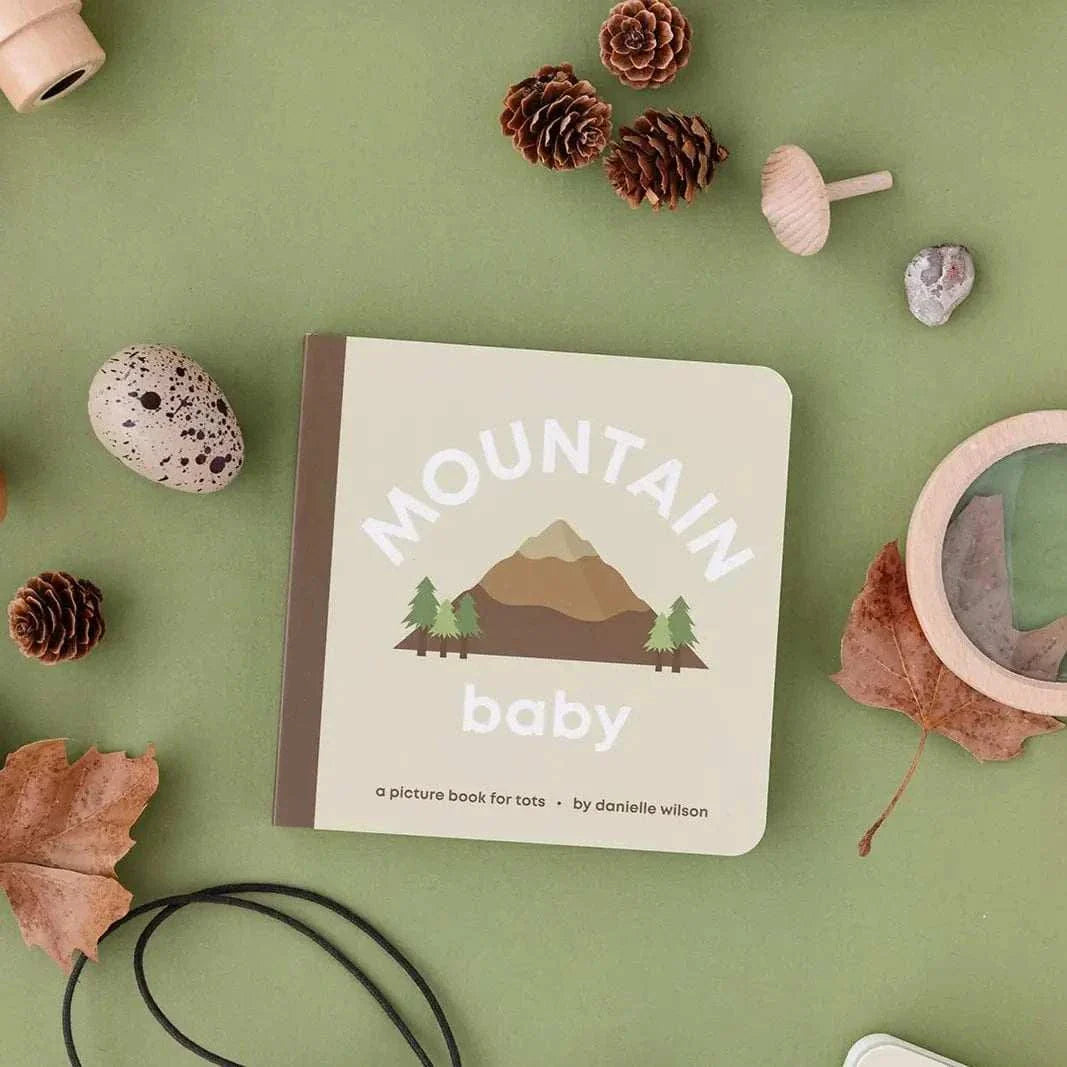 Mountain Baby book for toddlers with mountain illustration and nature-themed props on green background