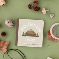Mountain Baby book for toddlers with mountain illustration and nature-themed props on green background
