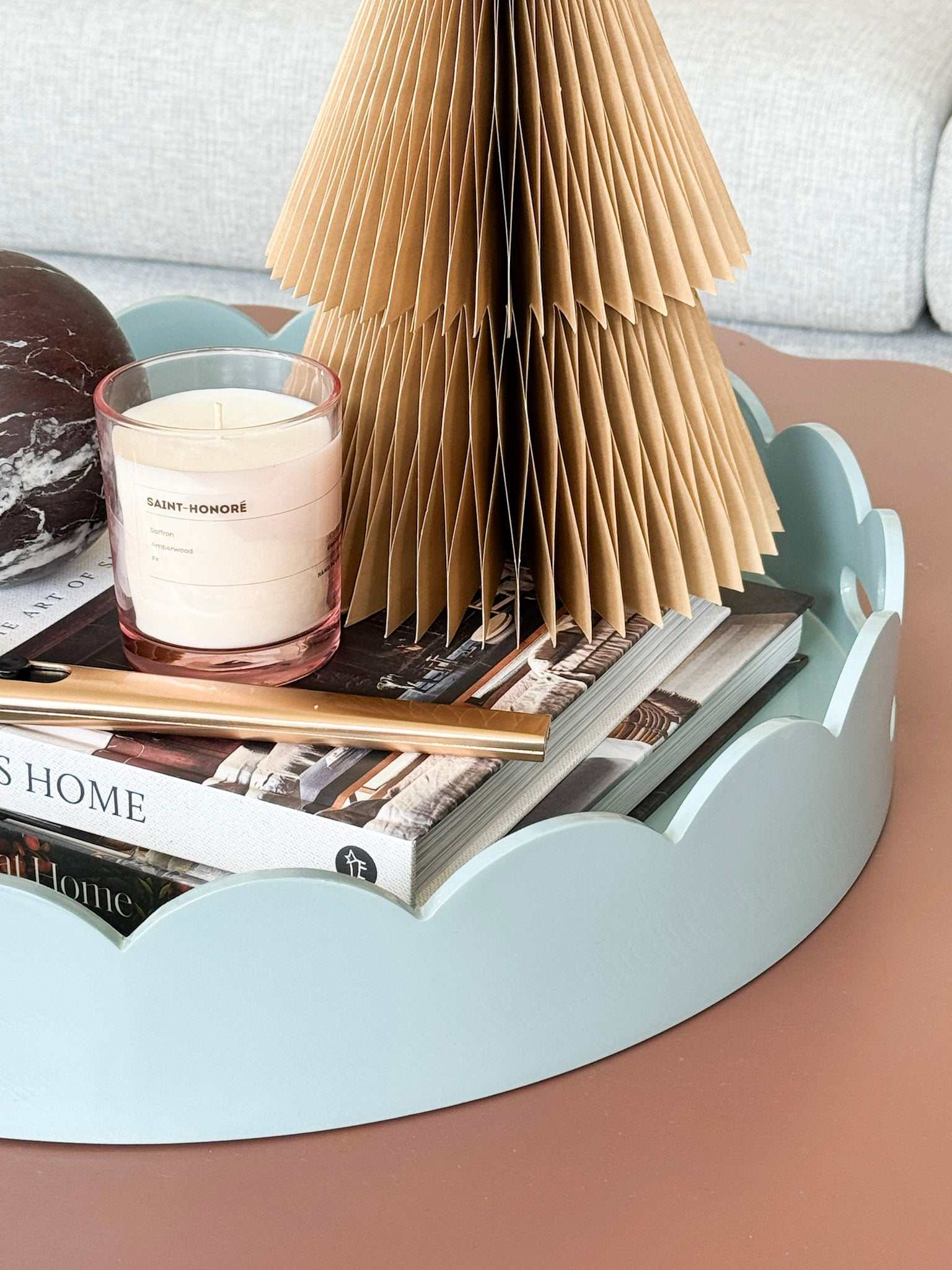 norsu Studio Round Scalloped Tray in duck egg blue with high-gloss lacquer finish and scalloped edges holding books, candle, and decor items