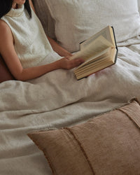 Reading in bed on Weave Home Sova Savanna pure linen sheets