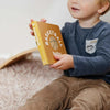 Baby holding the Basketball Baby board book with a basketball illustration on the cover