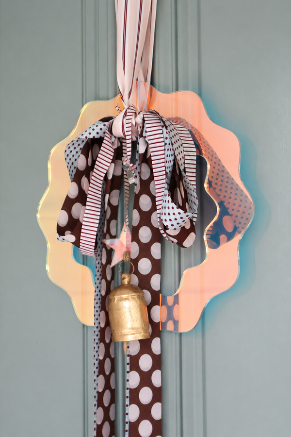 norsu STUDIO 33cm iridescent perspex Christmas wreath with hand-tied polka dot ribbons and a brass bell, on a green door